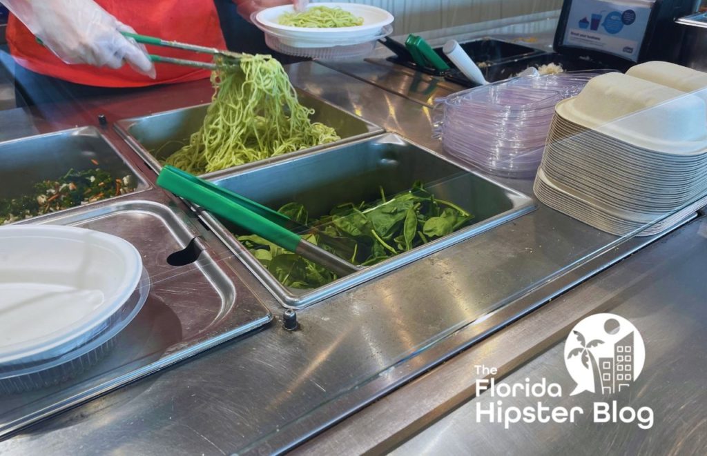 Bolay Gainesville Florida with worker gathering zucchini noodles. Keep reading to learn more about the best lunch in Gainesville. 