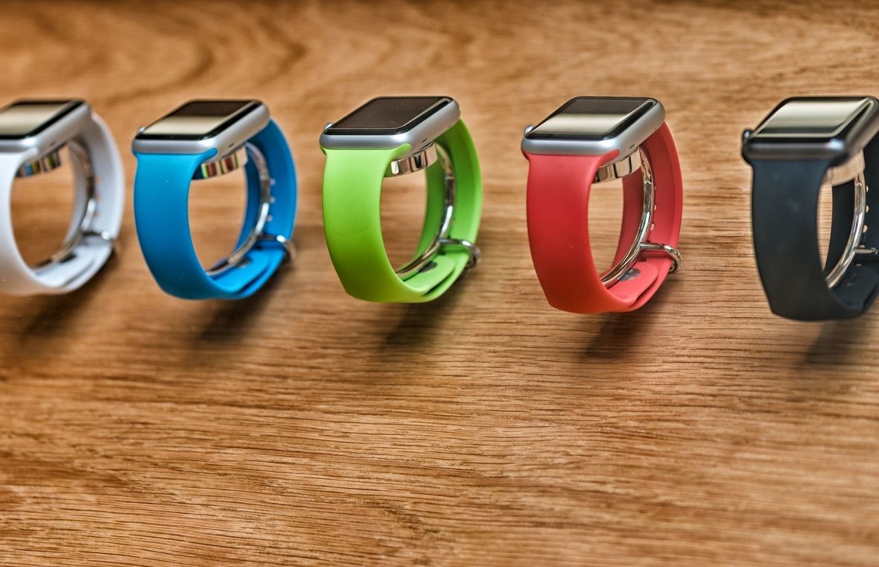 Rainbow color apple watches on wood panel Canva