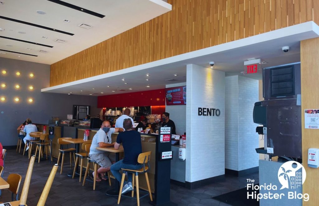 Inside Bento Restaurant in Orlando Florida. Two men sit at a high-top table near the counter. Keep reading to see what are the best places to get lunch in Orlando.