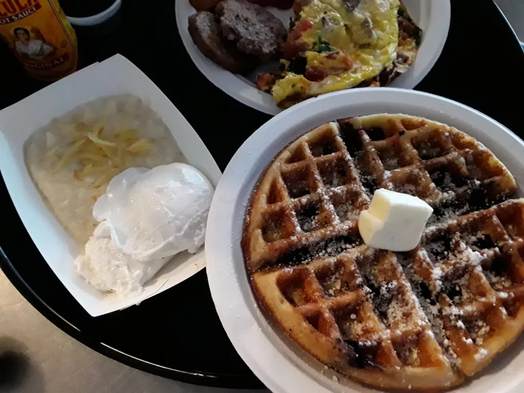 East End Eatery Breakfast with Grits Waffles Eggs and Sausage. One of the best places to get breakfast in Gainesville, Florida.