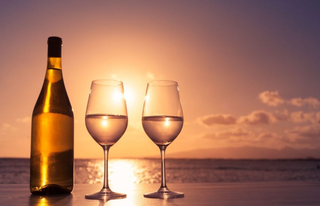 Two glasses of wine sit on a table overlooking a beach sunset in Florida. Keep reading for more places to take a perfect day trip from Orlando, Florida. 