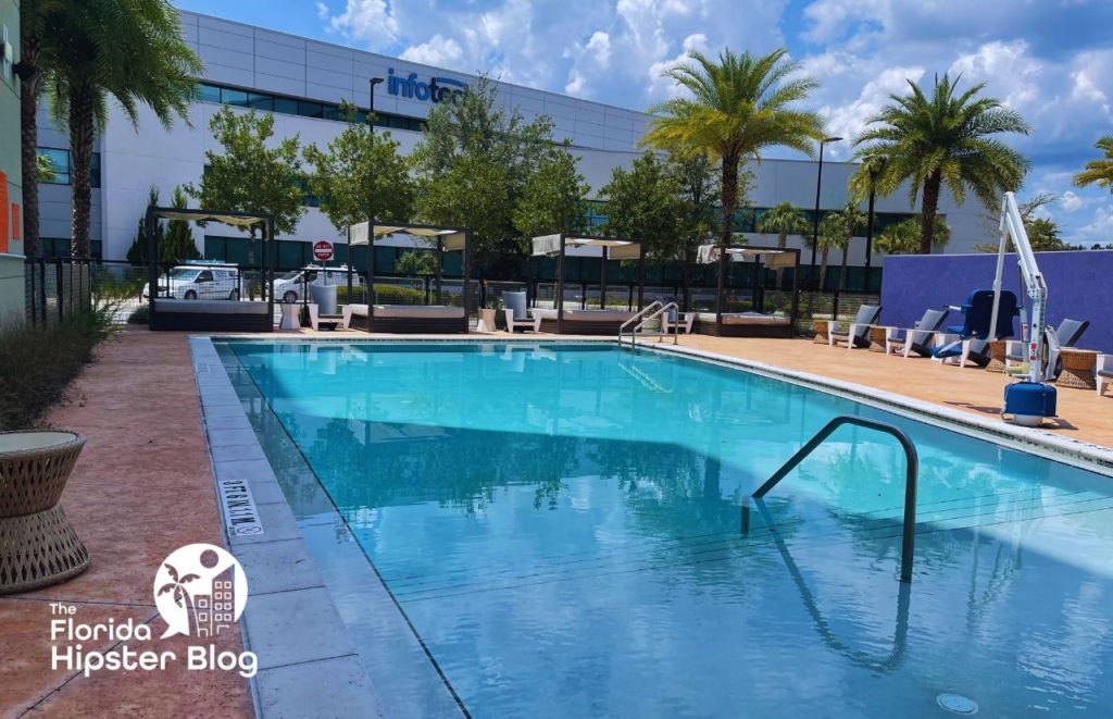 Hotel Indigo Gainesville Florida outdoor  pool area with sun loungers and tall palms. Keep reading to learn more about hotel indigo Gainesville Fl.