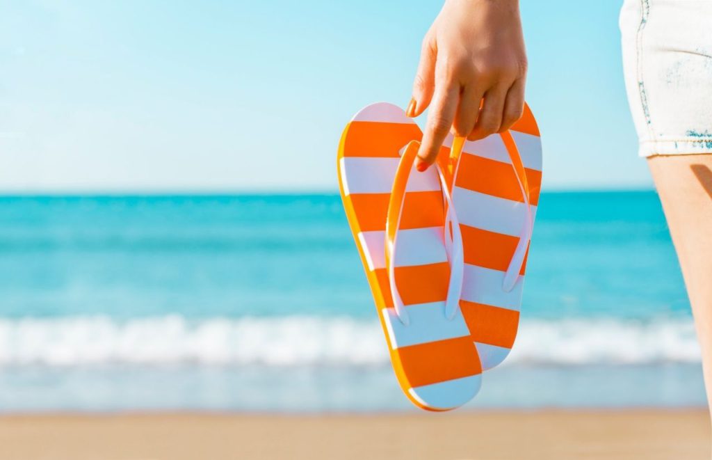 Orange and White Flip Flops on Florida Beach. Keep reading to learn more about visiting Florida in November.