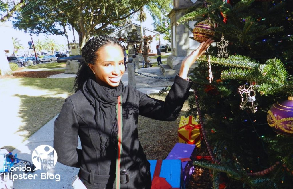 NikkyJ holding ornaments on Christmas tree in St Augustine Florida. Keep reading for the best things to do in St. Augustine for Christmas!