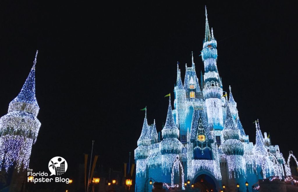 Cinderella Castle decked out in white Christmas Lights Magic Kingdom. One of the best things to do in Orlando for Christmas.