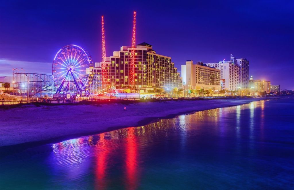 A nighttime view of a lit Daytona Beach skyline in Daytona Beach, Florida. Keep reading for more places to take a perfect day trip from Orlando, Florida. 