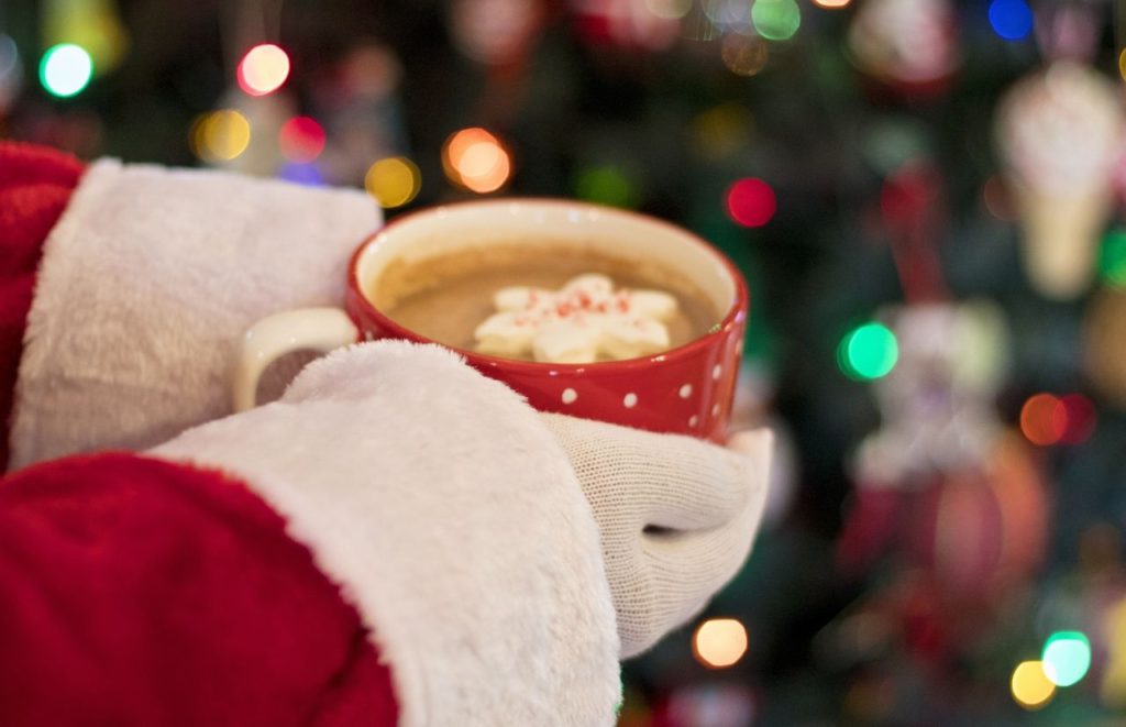 Santa holding cup of hot cocoa at Tree Lighting and Symphony in Lights at Wiregrass Shops in Wesley Chapel. Keep reading to learn about the best things to do in Tampa for Christmas 2023.