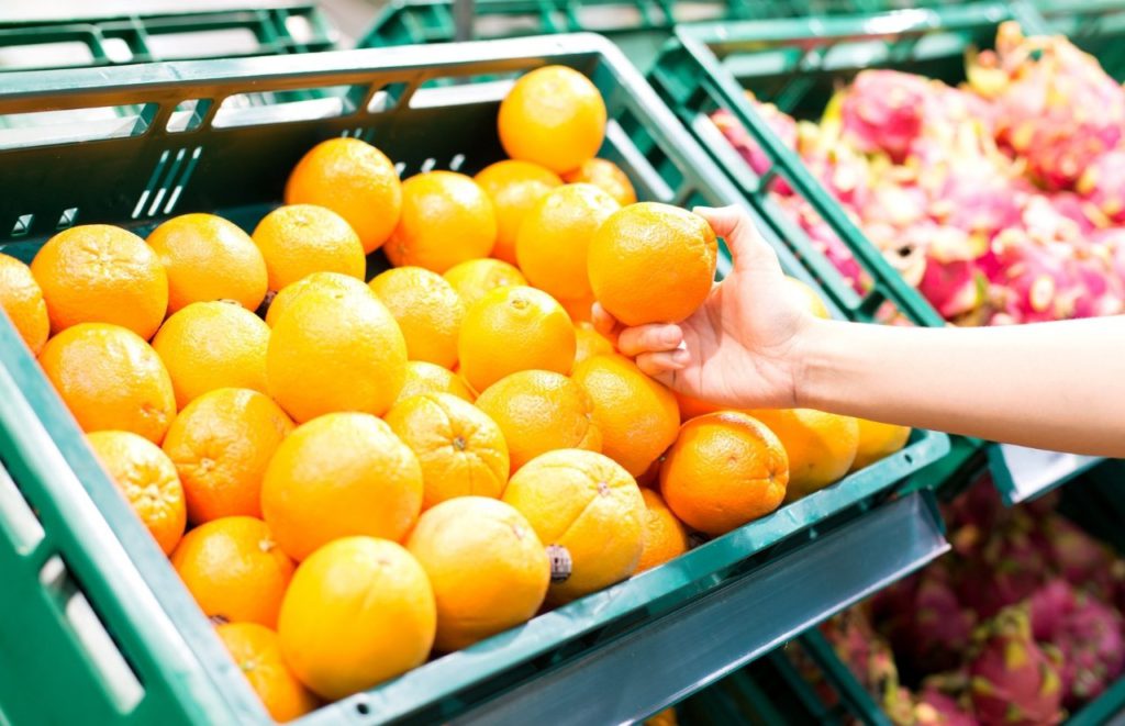 Freshfield Orlando Farm Supermarket with lady grabbing oranges. Keep reading to find out more about the best farms to visit in Orlando.