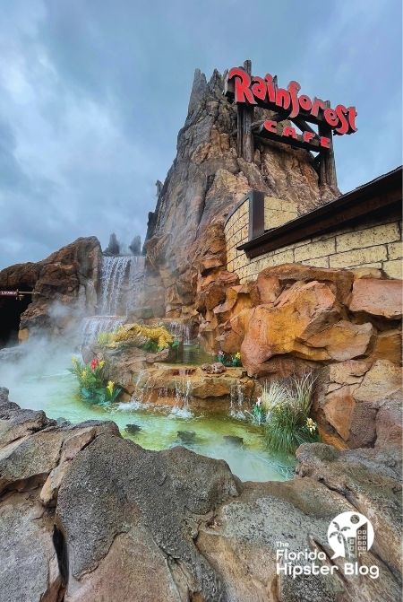 Rainforest Cafe exterior with a cascading waterfall on a cloudy Orlando Florida day. Keep reading to discover more about the best kid restaurants in Orlando. 