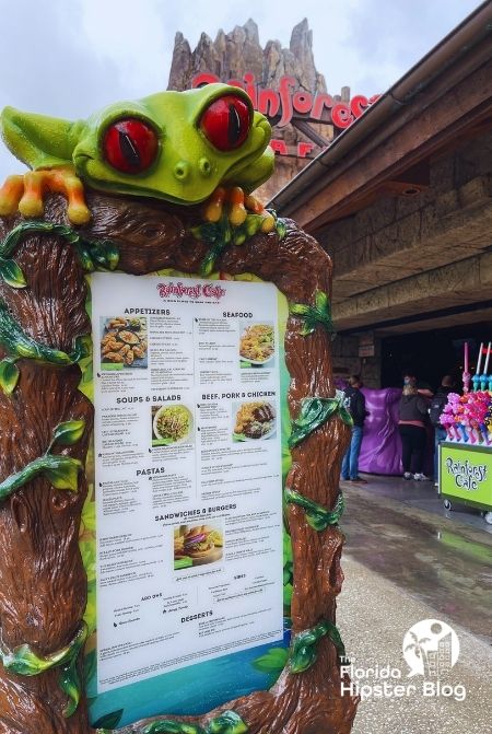 Rainforest Cafe Menu Disney Springs Orlando Florida with a frog leaning over top. Keep reading to find out the best kid restaurants in Orlando. 