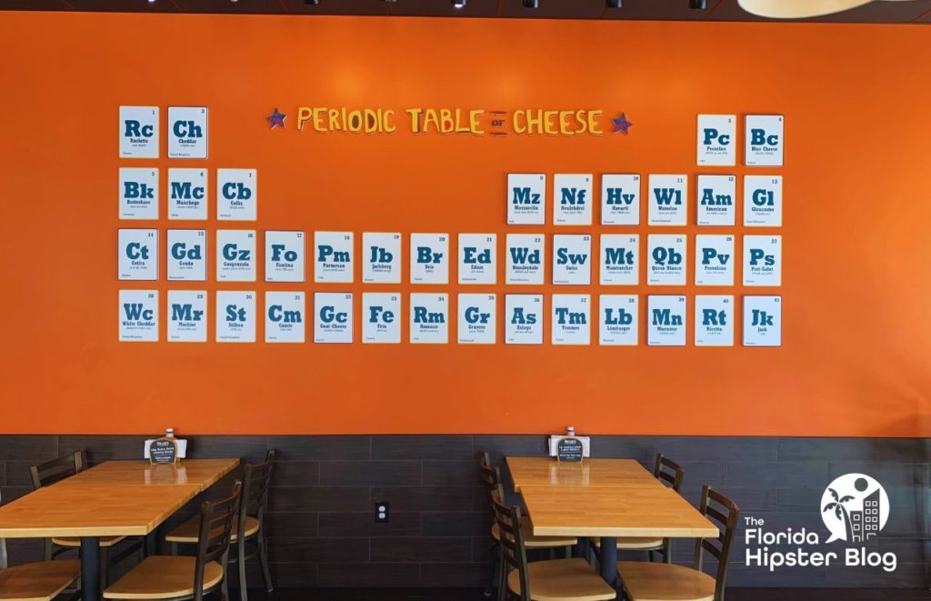 Toasted Orlando Periodic Table of Cheese. Periodic table with variety of cheeses hangs on orange wall above several tables. Keep reading to see what are the best places to get lunch in Orlando.
