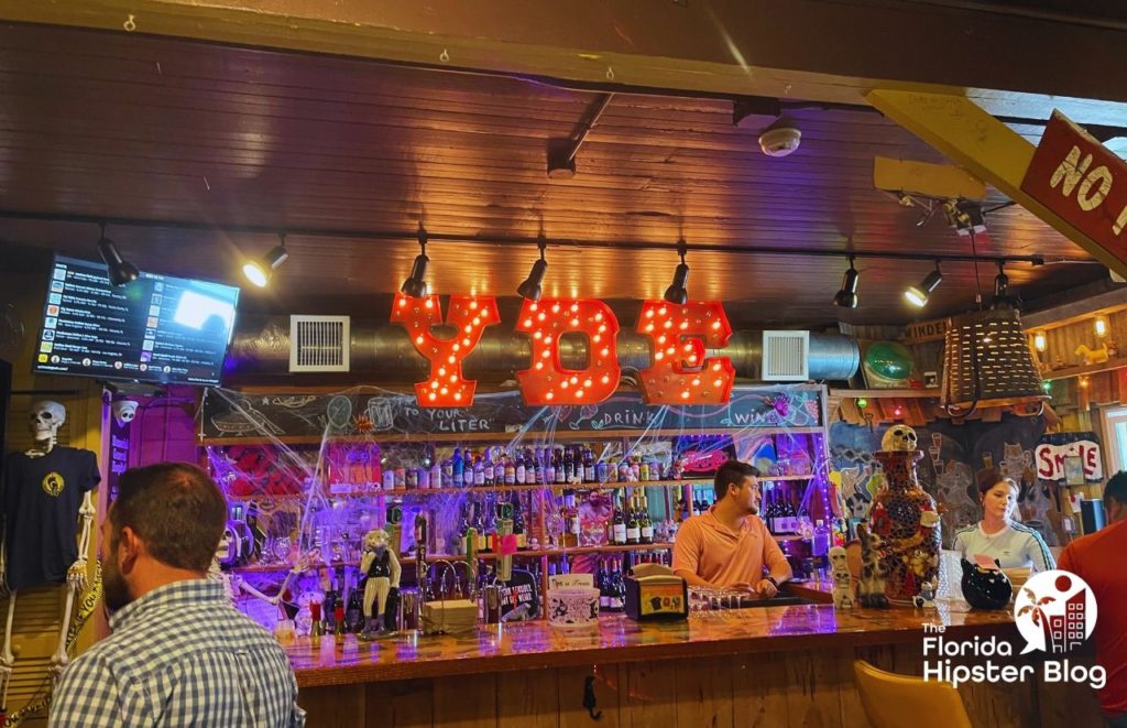 Yellow Dog Eats counter area with red  YDE letters with lights hanging over a bar. Several people stand behind the counter. Keep reading to see what are the best places to get lunch in Orlando.