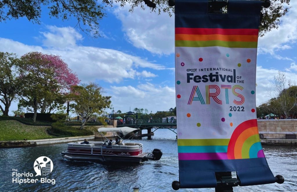 Epcot Festival of the Arts sign with a boat going by in the water in the backdrop. Keep reading to learn more about things to do in Orlando for couples.