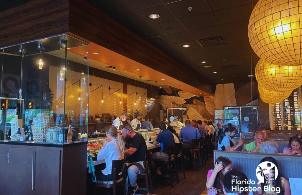 People dine at Seito Sushi in Orlando, Florida. The interior has warm lighting, cozy booths, and open view of the sushi preparation. Keep reading for more on the best restaurants in Orlando, Florida. 