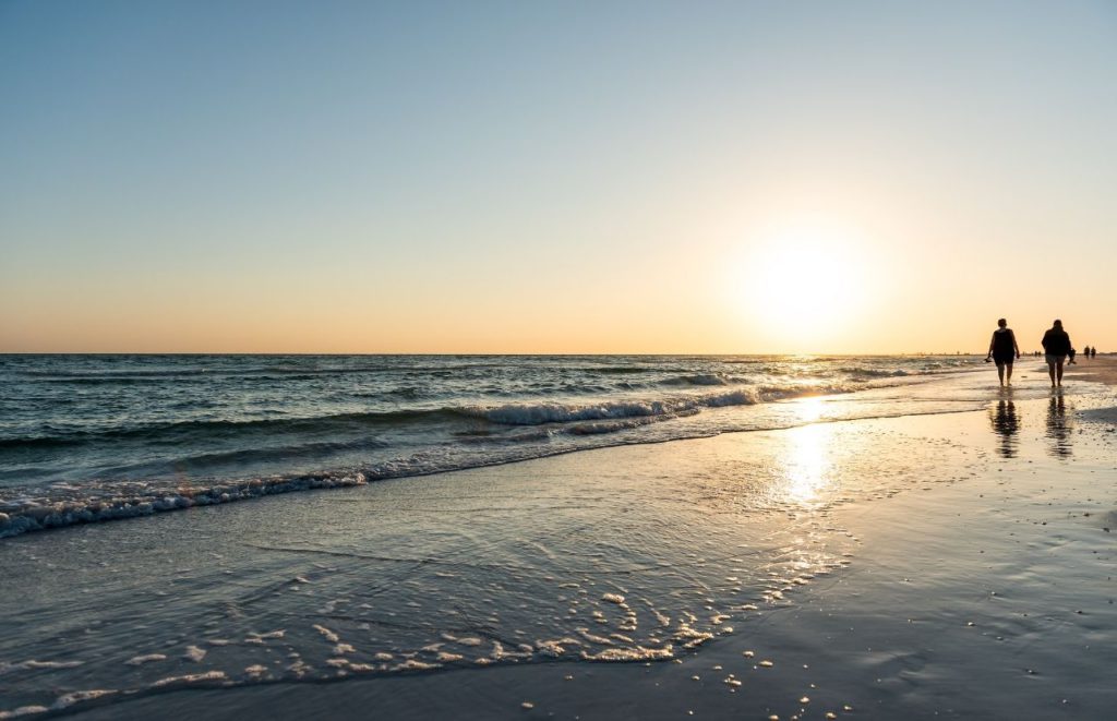 Sarasota Beach Florida with couple walking in a silhouette near the Gulf of Mexico. Keep reading to get the best days trips from The Villages, Florida.