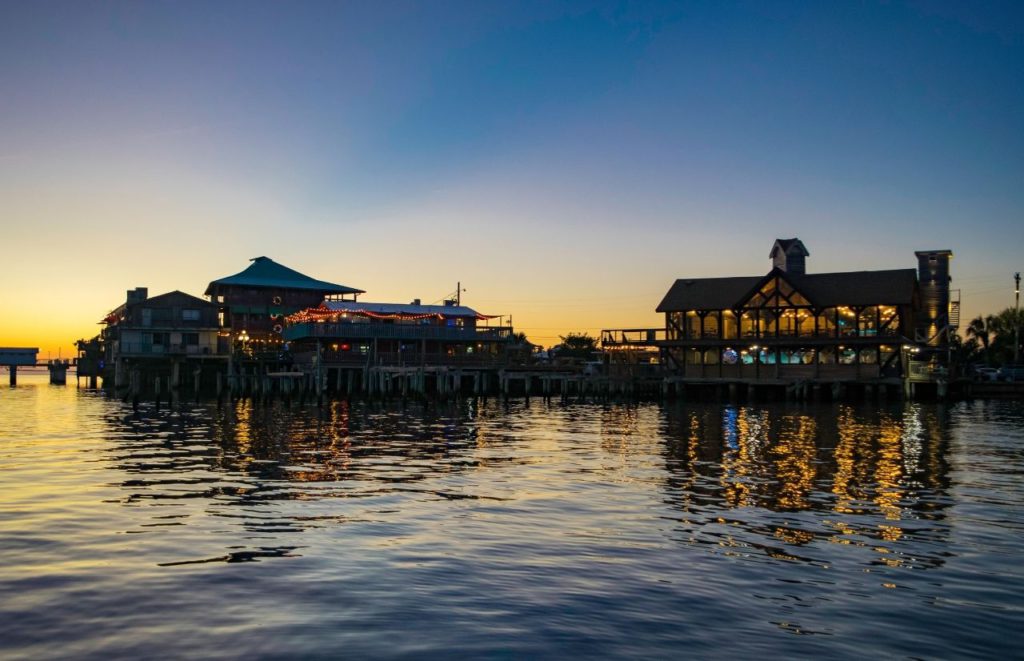 Homes overlook the water at sunset 
 in Cedar Key in Florida. Keep reading for more places to take a perfect day trip from Orlando, Florida. 