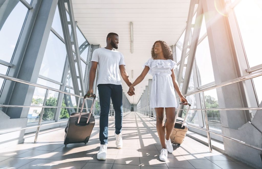 Can I Take a Backpack and a Carry-On black couple walking through airport. Keep reading for all you need to know about taking both a backpack and a carry-on for your next flight. 