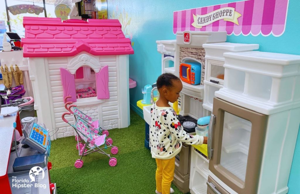 Little black girl playing in the kitchen at My Little Town in Orlando Florida, Keep reading to discover all you need to know about the best places to celebrate birthday in Orlando.