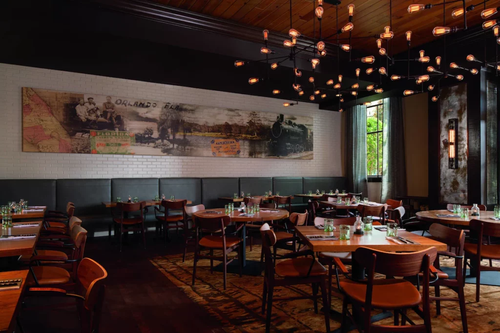 Highball and Harvest at the Ritz Carlton Grande Lakes in Orlando interior dining area with hanging lights and dark wood decor. Keep reading to learn the best places to go for breakfast buffet in Orlando. 