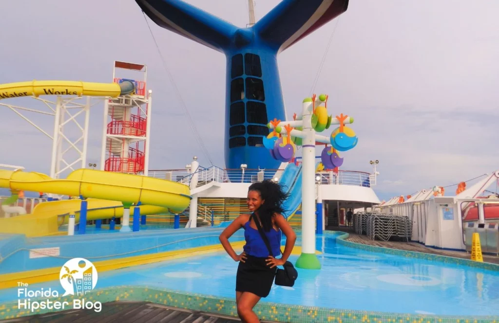 Woman poses in front of water slides and pool area on Carnival cruise ship in Florida. Keep reading for more romantic getaways in Orlando.