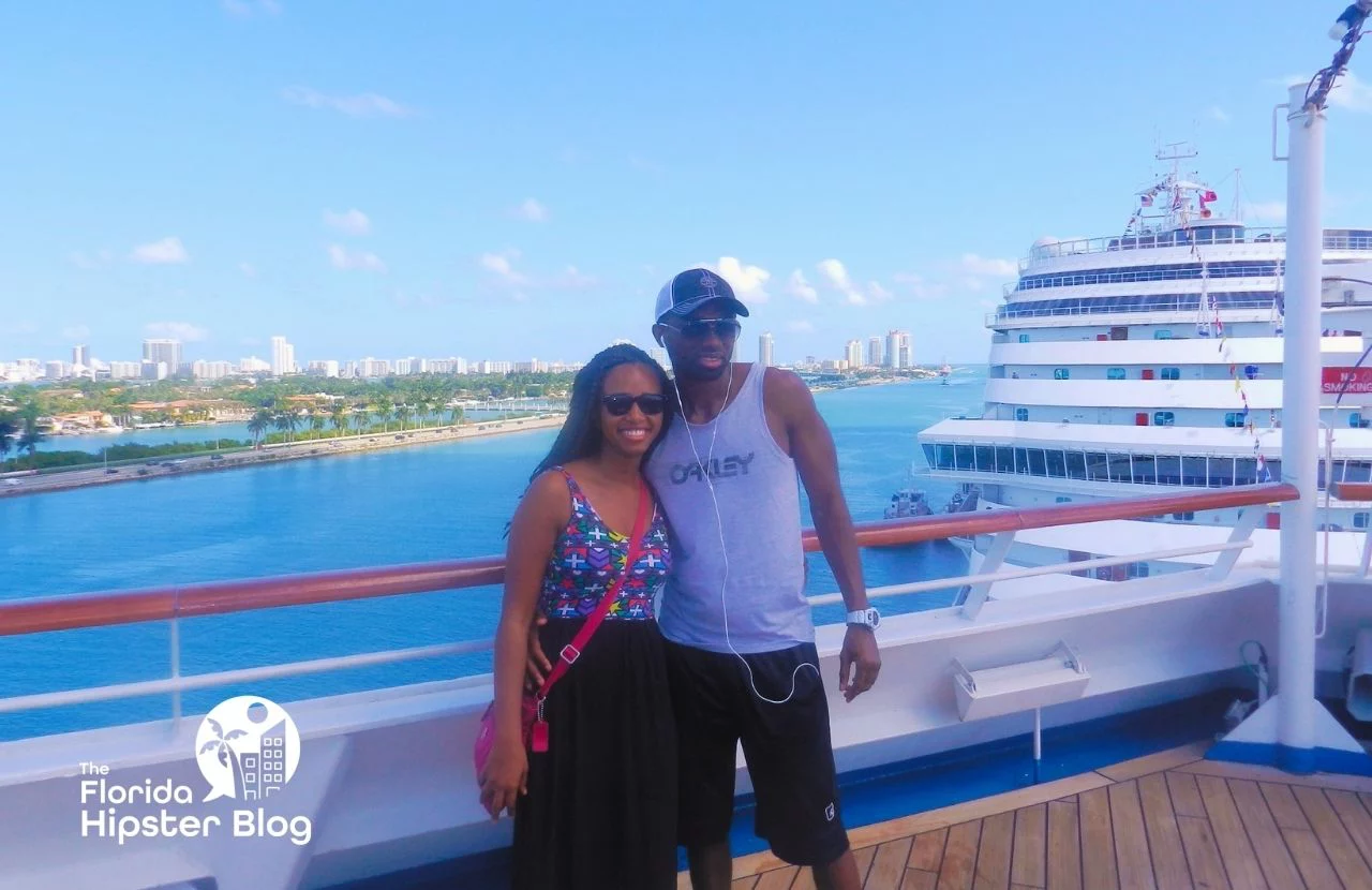 Couple poses on cruise ship overlooking water as it exits port in Florida. Keep reading for more romantic getaways in Orlando.