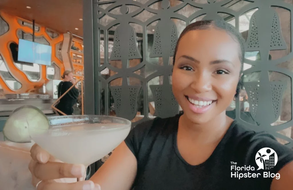 Woman holds drink in a martini glass at the Dahlia Lounge  at Walt Disney World in Orlando, Florida. Keep reading for more romantic getaways in Orlando.