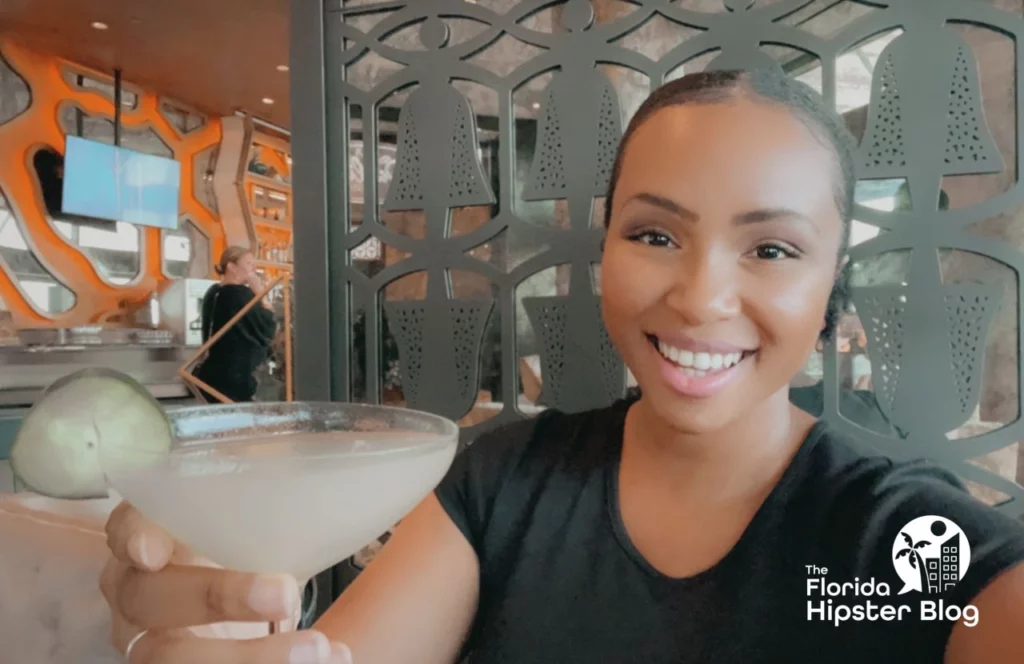 Woman holds drink in a martini glass at the Dahlia Lounge at Walt Disney World in Orlando, Florida. Keep reading for more romantic getaways in Orlando.