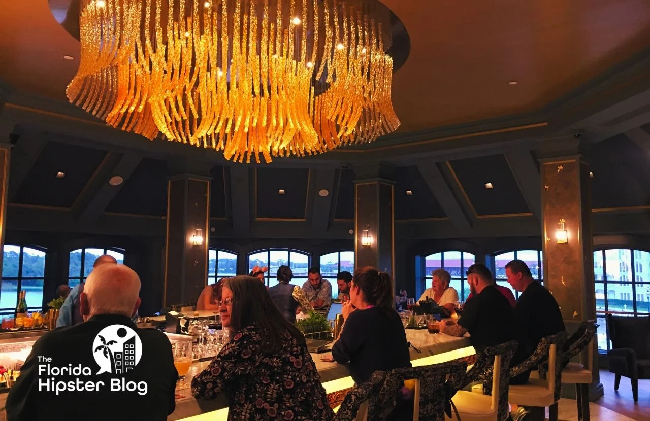 People sit at bar under massive chandelier at the Enchanted Rose Lounge in Orlando, Florida. Keep reading for more romantic getaways in Orlando.