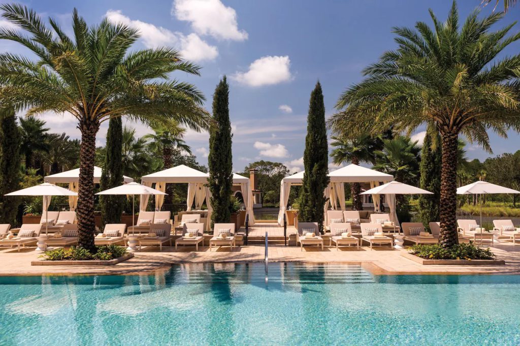 The pool at Four Seasons Resort Orlando at Walt Disney World Resort in Orlando, Florida features lounge chairs with pillows and curtained cabanas. Keep reading for more options for where to stay in Orlando, Florida.