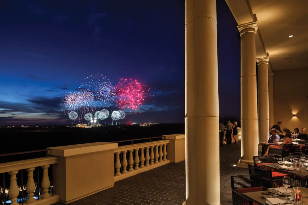 The balcony at Capa at Four Seasons Orlando features stone columns and a view of the fireworks in Orlando, Florida. Keep reading for more on the best restaurants in Orlando, Florida. 
