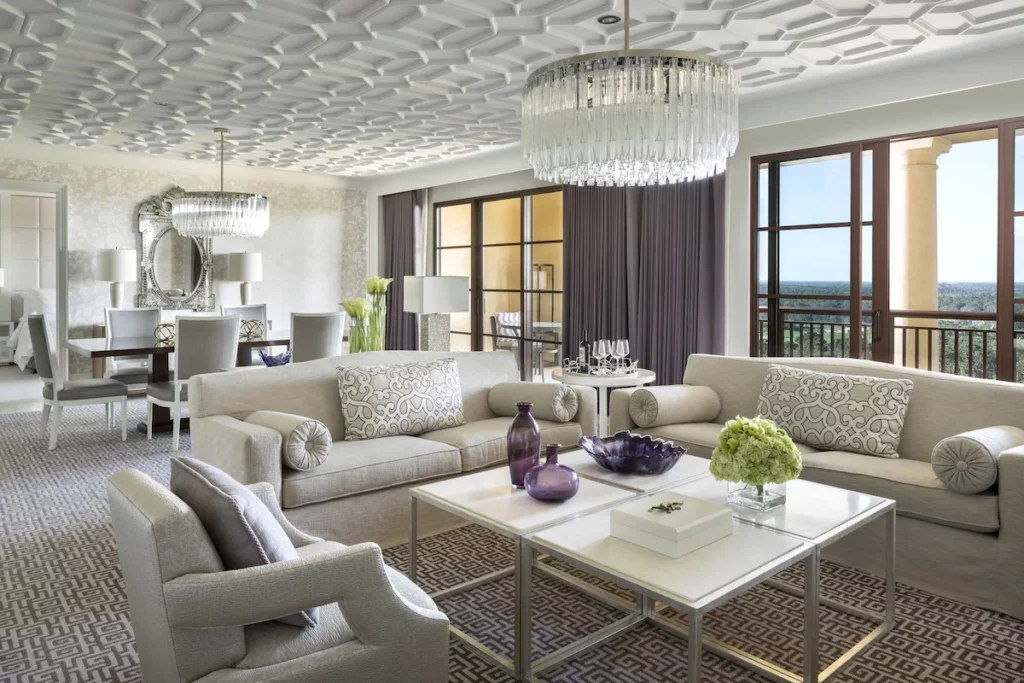 Interior view of a room at the Four Seasons Resort Orlando at Walt Disney World Resort in Orlando, Florida. It has multiple couches, a large dining room table and view of the area. Keep reading for more options for where to stay in Orlando, Florida. 