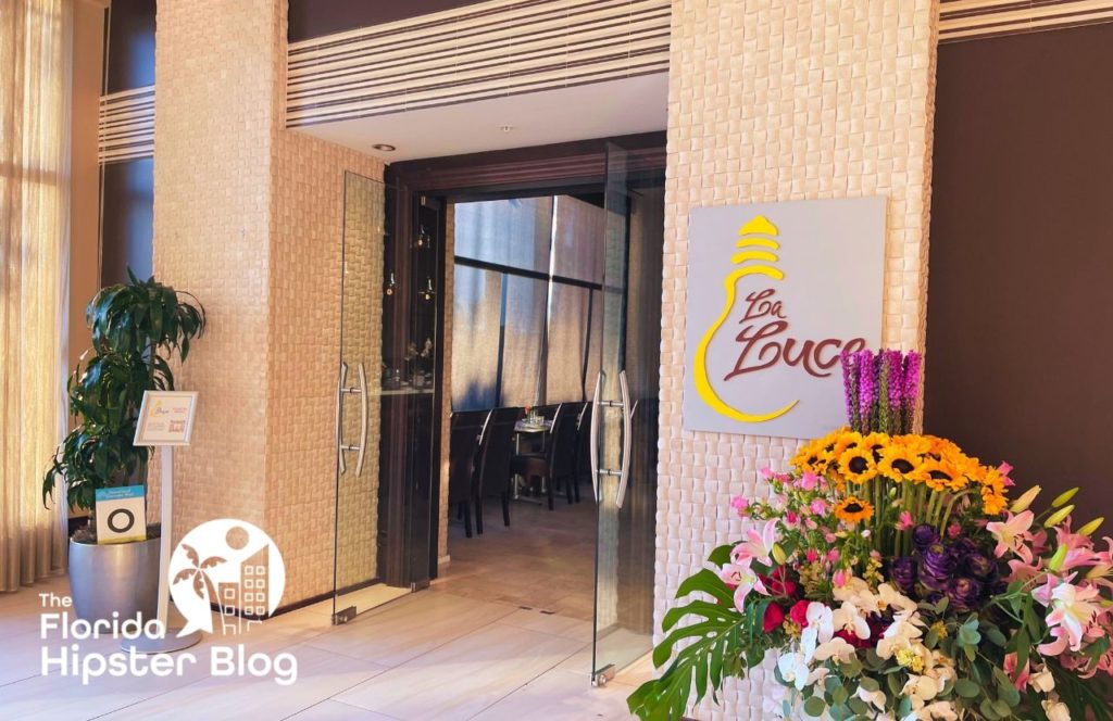 The entrance of La Luce at the Signia by Hilton Orlando Bonnet Creek in Orlando, Florida is surrounded by flowers. Keep reading for more on the best restaurants in Orlando, Florida. 