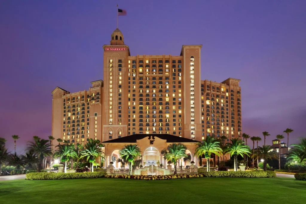 The exterior of the JW Marriott Orlando, Grande Lakes in Orlando Florida is a big gold building with a fountain and large lawn in the front. Keep reading for more options for where to stay in Orlando, Florida.