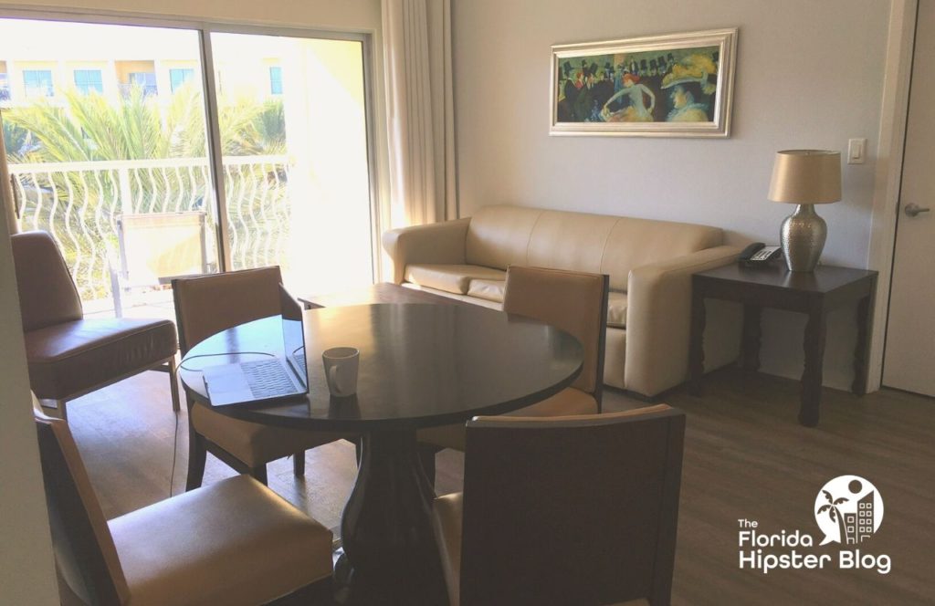 The interior of a room at Melia Orlando Celebration in Orlando, Florida includes a table with four chairs and couch. Keep reading for more options for where to stay in Orlando, Florida. 