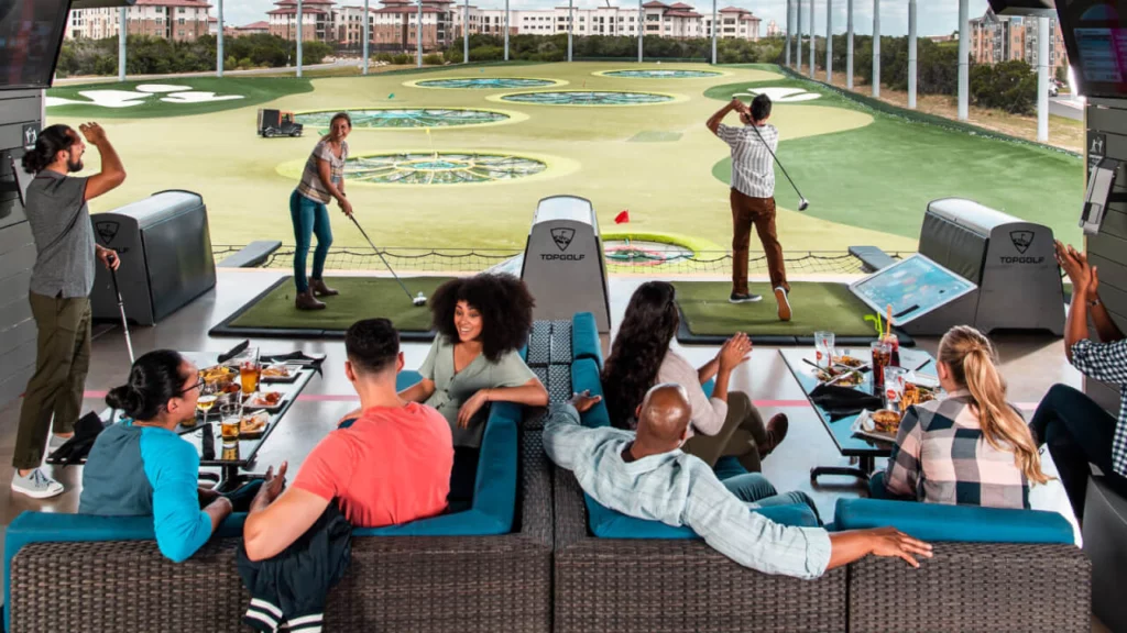 Adults playing golf and enjoying food and drinks at Top Golf. Keep reading to learn more ideas of fun things to do in Orlando tonight.
