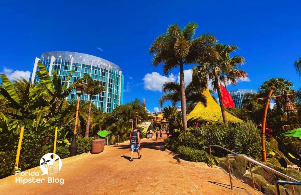 A man walks down a sidewalk surrounded by palm trees at Universal Orlando Cabana Bay Beach Resort in Orlando, Florida. Keep reading for more options for where to stay in Orlando, Florida.
