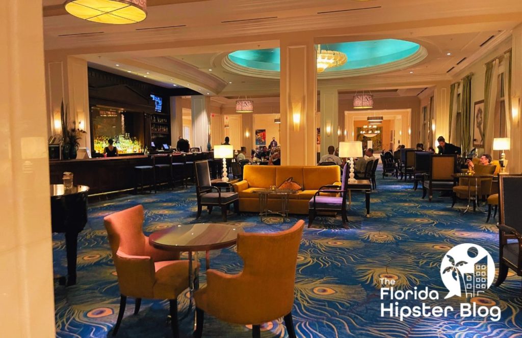 The lobby at the Waldorf Astoria in Orlando, Florida has blue and gold carpet, orange seating and a bar area. Keep reading to learn the best places to stay in Orlando. 