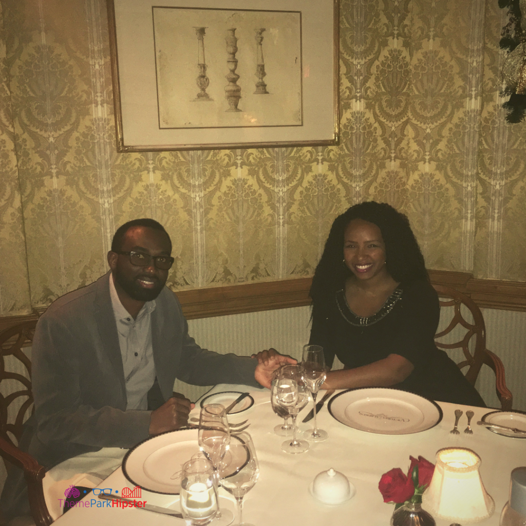 A couple holds hands and smiles while enjoying date night at Victoria and Albert's in Orlando, Florida. Keep reading for more on the best restaurants in Orlando, Florida. 
