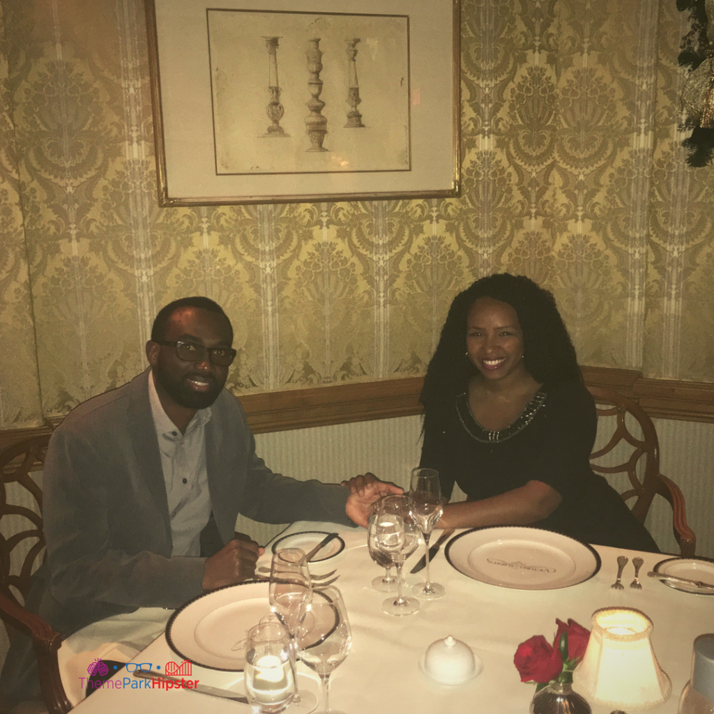 A couple holds hands and smiles while enjoying date night at Victoria and Albert's in Orlando, Florida. Keep reading for more on the best restaurants in Orlando, Florida.