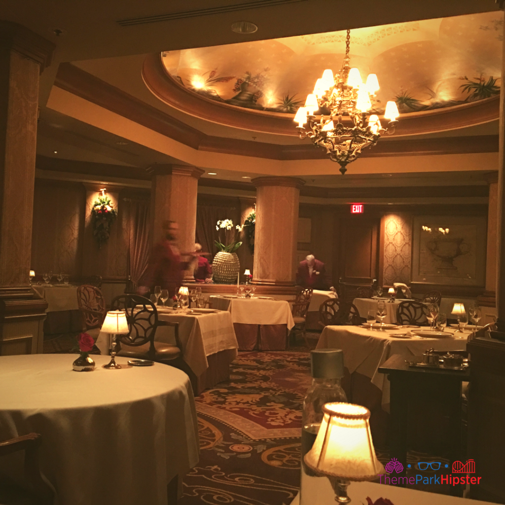 A chandelier and cloth-covered tables sit in a dimly lit room at Victoria and Albert's in Orlando, Florida. Keep reading for more on the best restaurants in Orlando, Florida.