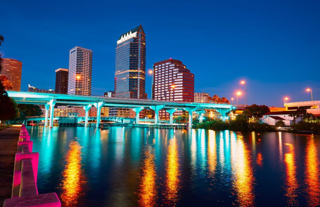 Downtown Tampa after sunset with glowing lights of the city reflecting on the waterfront. Keep reading to get the best places to watch sunset in Tampa.