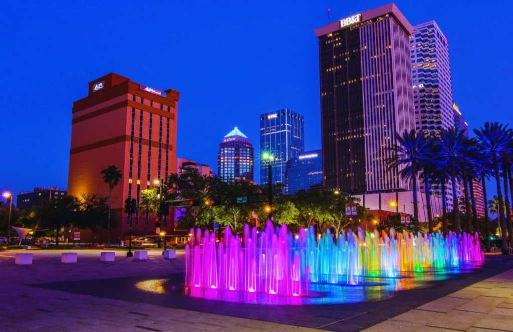 A fountain in downtown Tampa, Florida is lit up with purple, blue, green, and orange lights. Keep reading for more places to take a perfect day trip from Orlando, Florida.