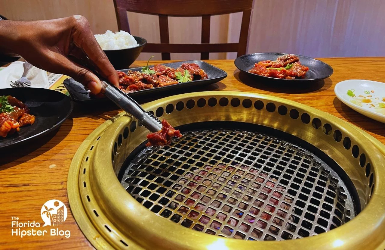 Gyu-Kaku Japanese BBQ Dining Restaurant in Orlando, Florida Marinated beef being placed on hot grill. Keep reading to get the best lunch in Orlando!