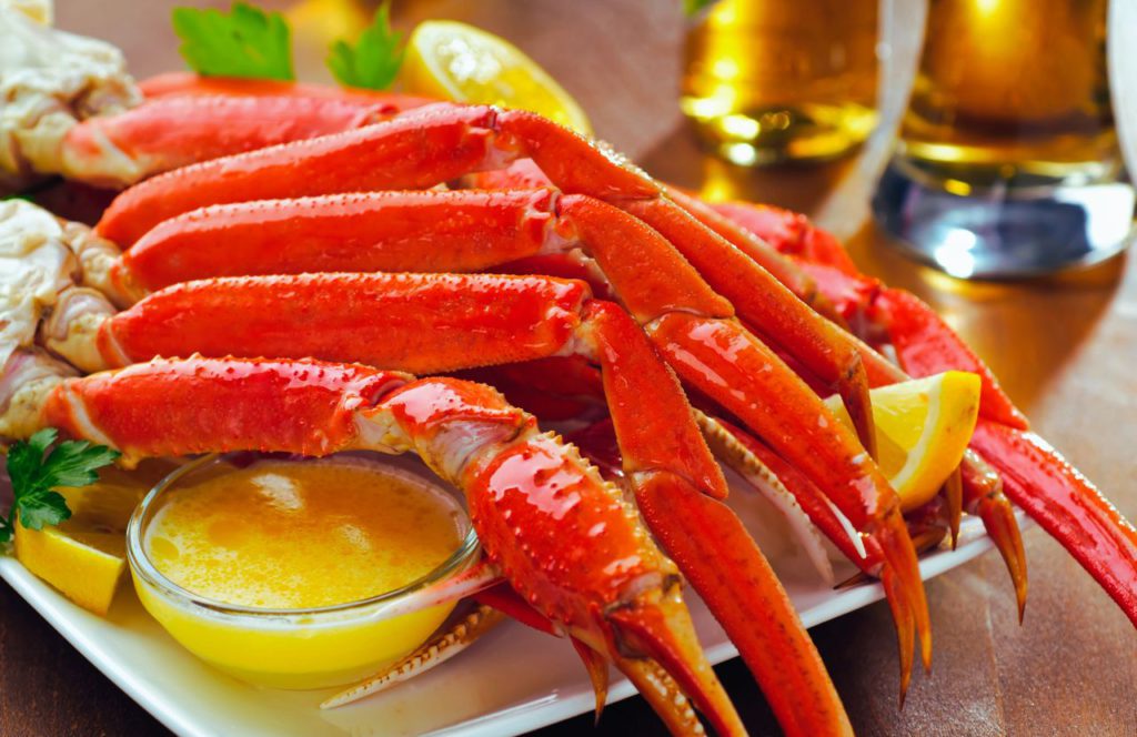 Plate full of crab legs and melted butter with beers on the table. Keep reading to find out what to do in Cape San Blas. 