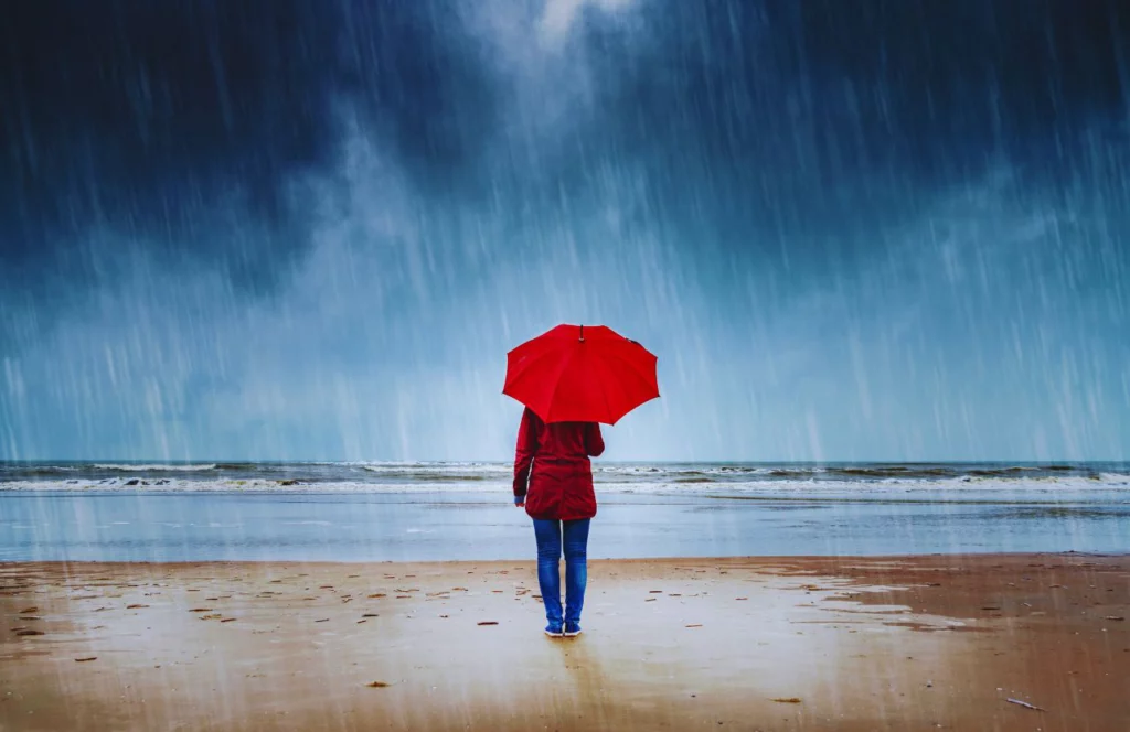 Lady in Rain Storm with Red Umbrella. Can I bring umbrella on plane? Keep reading to learn how.