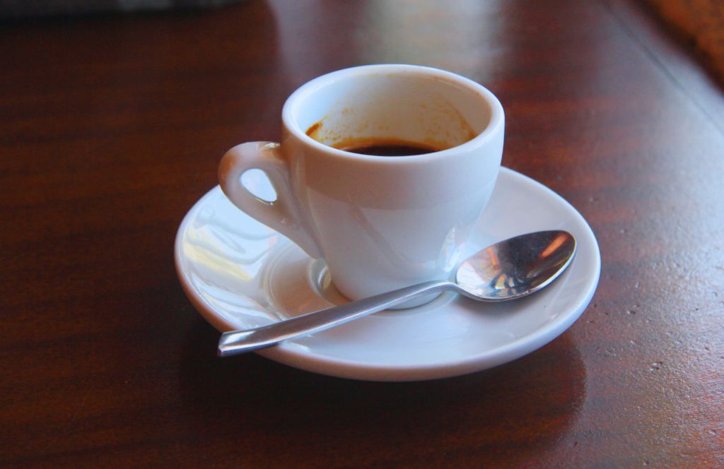 Cup of coffee with a spoon on the table. Keep reading to find out about the best Gainesville hotels.