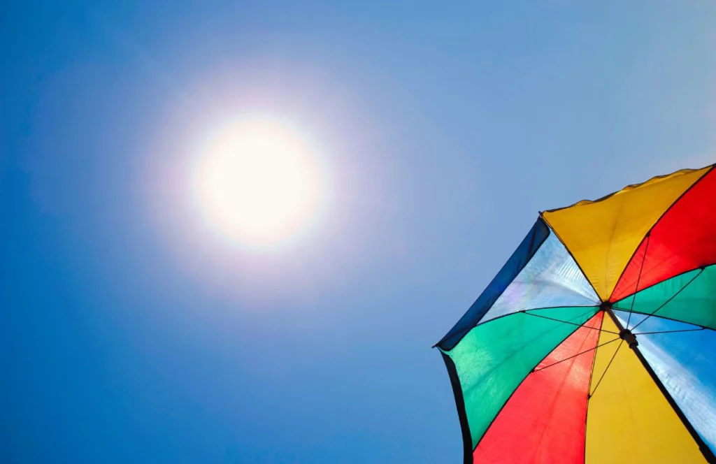 Rainbow umbrella in the Florida sun. Lady on Wooden Bridge in rain overlooking lake. Can I bring umbrella on plane? Keep reading to learn how.