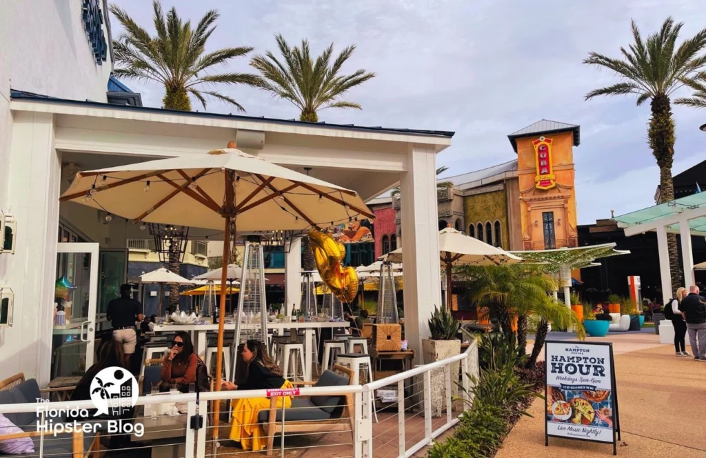 The Hampton Social Restaurant in Orlando, Florida Outdoor Patio with Happy Hour Sign. Keep reading to know the best time to travel to Orlando, Florida!