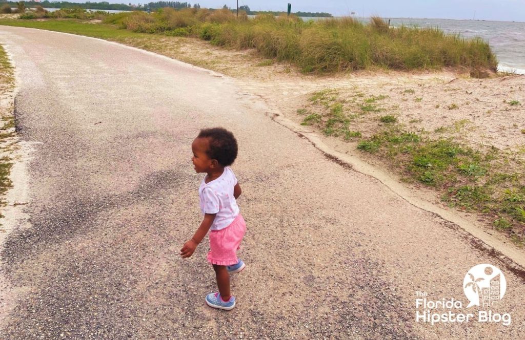 Cypress Point Beach Park on Cloudy Rainy and windy day with little toddler girl on path. Keep reading to find out what to do in Tampa that is free.  