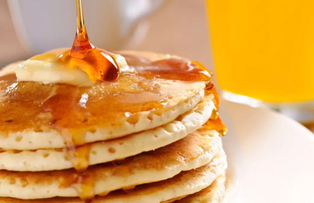 Pouring Syrup on Pancakes at Canopy Road Cafe Keep reading to learn about the best breakfast in Tampa.